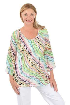 Woman wearing a colorful patterned top on a white background.