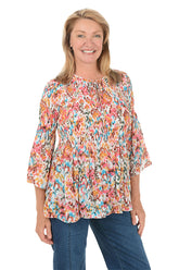 Woman wearing a colorful floral blouse and blue jeans on a white background.