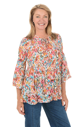 Woman wearing a colorful floral blouse and blue jeans on a white background.
