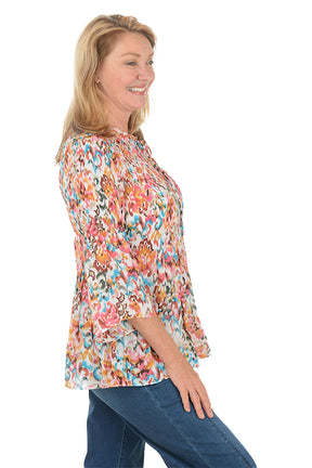 Woman wearing a colorful floral blouse and blue jeans on a white background. Side shot.