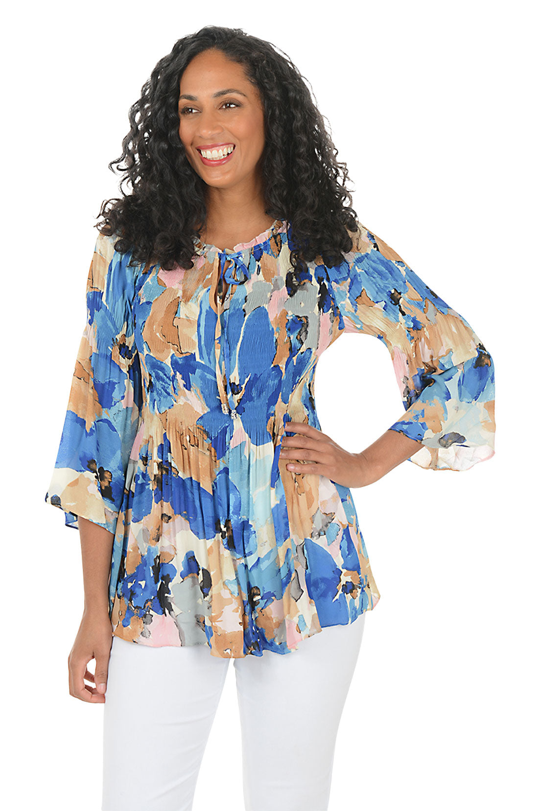 Woman wearing a colorful floral blouse with white pants on a white background. Second front shot.