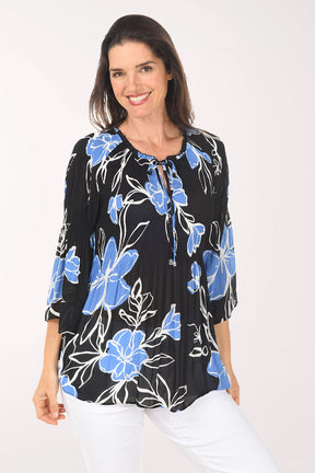 Woman wearing a black floral blouse with blue flowers on a white background