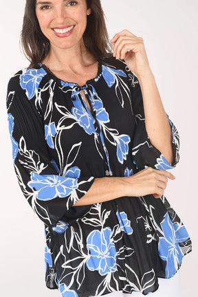Woman wearing a black floral blouse with blue flowers on a white background