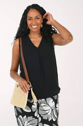 Woman wearing a black sleeveless top and patterned pants on a white background