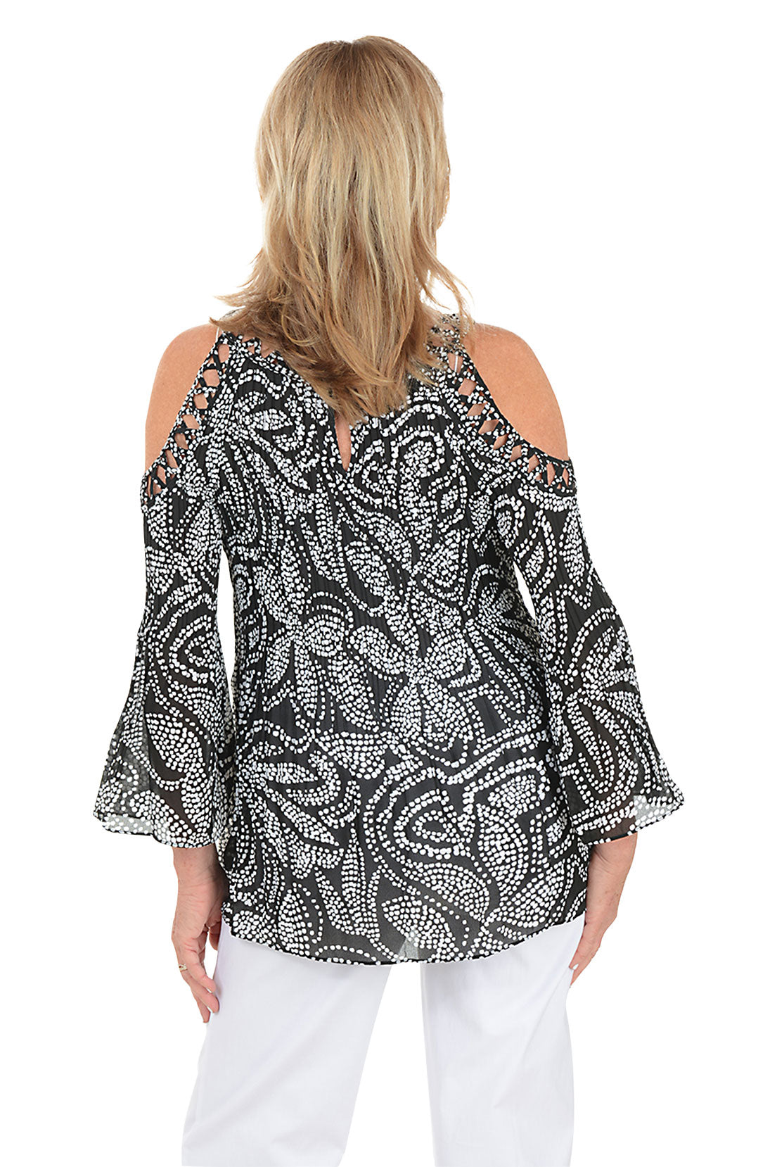 Woman wearing a black and white patterned blouse with cold shoulder design on a white background. Back shot.