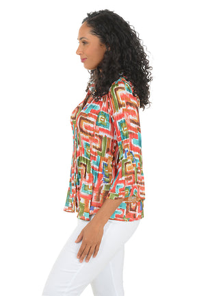 Woman wearing a colorful patterned blouse with white pants on a white background. Side shot.