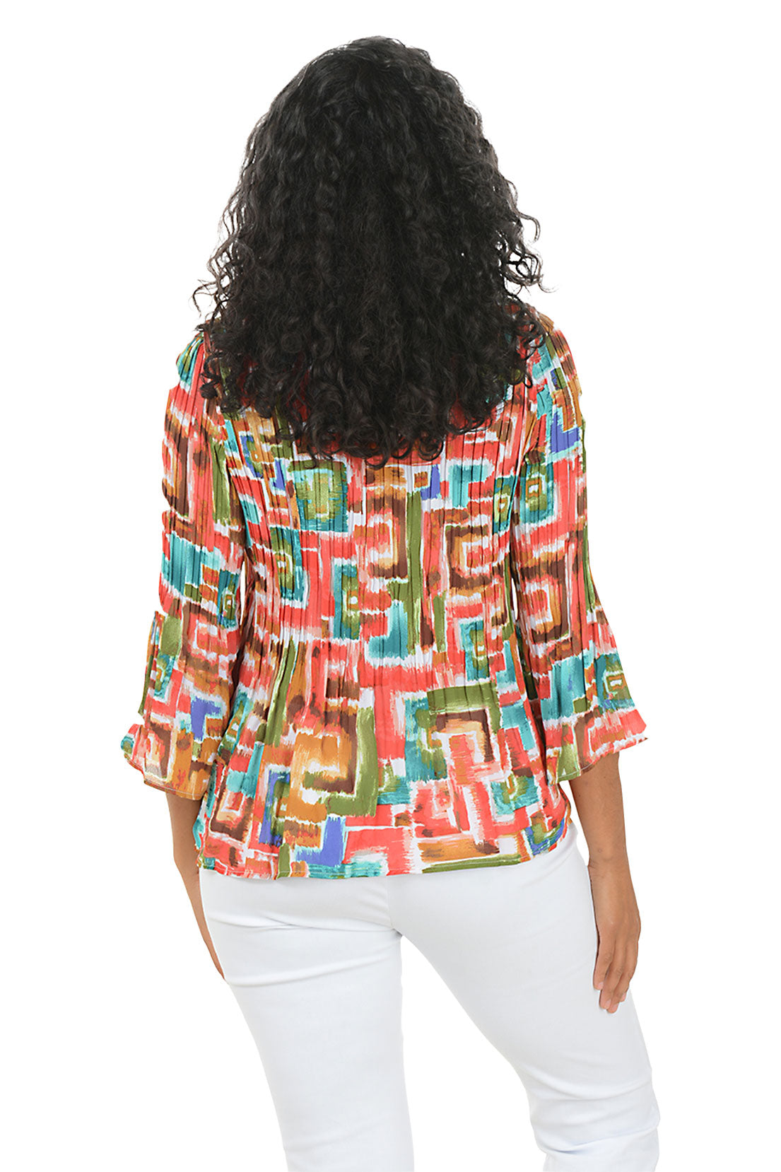 Woman wearing a colorful patterned blouse with white pants on a white background. Back shot.