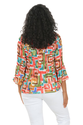 Woman wearing a colorful patterned blouse with white pants on a white background. Back shot.