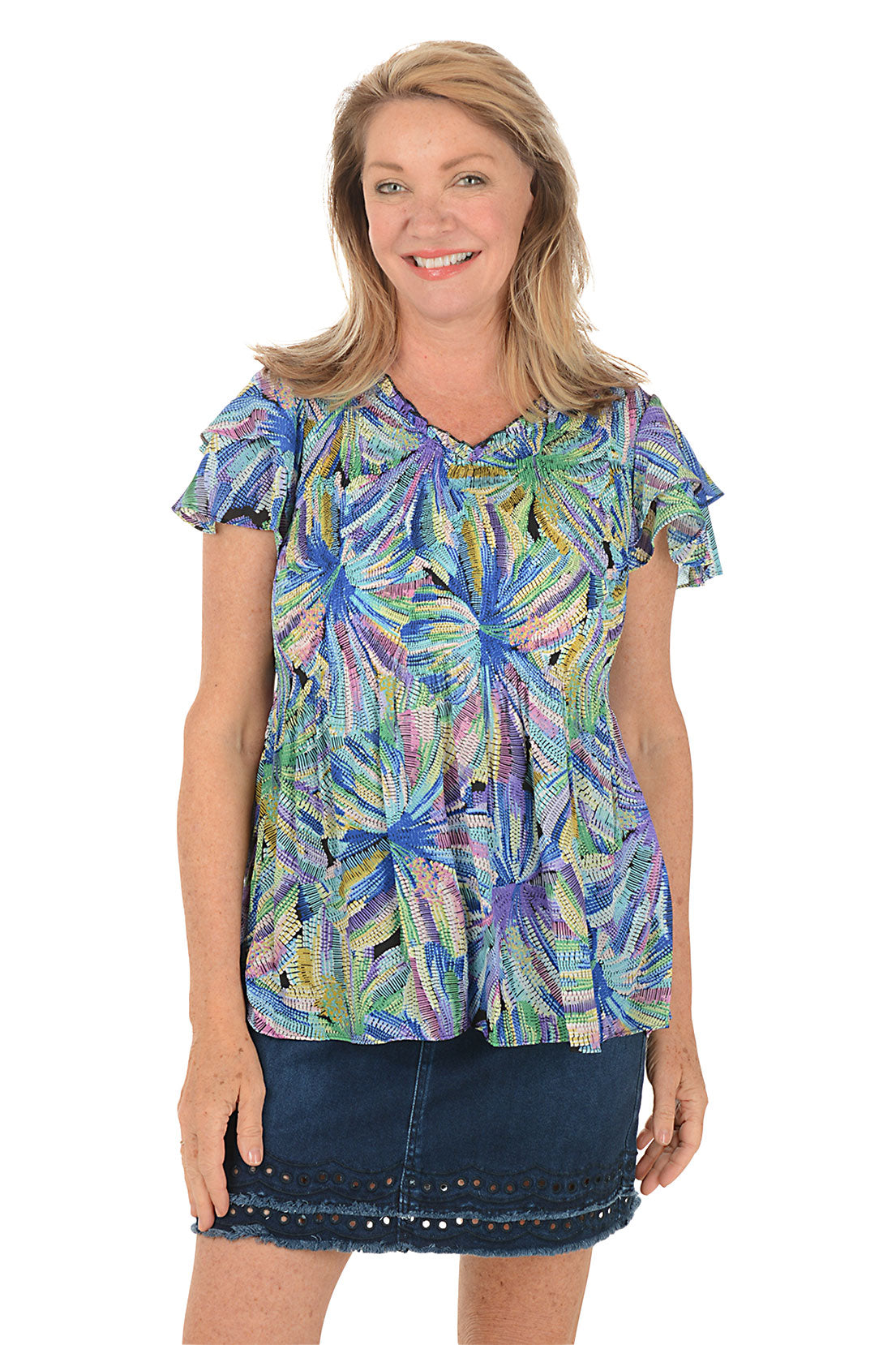 Woman wearing a colorful floral blouse with a white background.