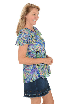 Woman wearing a colorful floral blouse with a white background. Side shot.