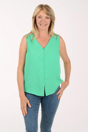 Woman wearing a green sleeveless blouse and blue jeans on a white background