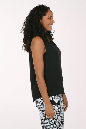 Woman wearing a black sleeveless top and patterned pants on a white background