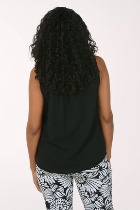 Woman wearing a black sleeveless top and patterned pants on a white background