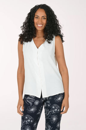 Woman wearing a white sleeveless top and black floral pants on a white background