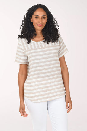 Woman wearing a striped shirt and white pants on a plain background