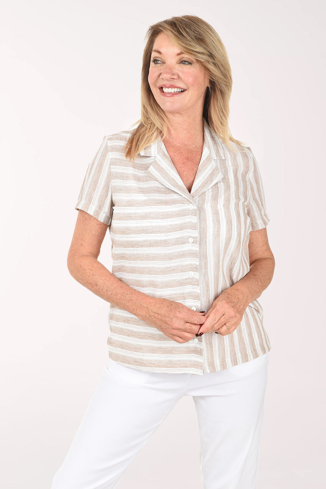 Woman wearing a striped shirt and white pants on a plain background