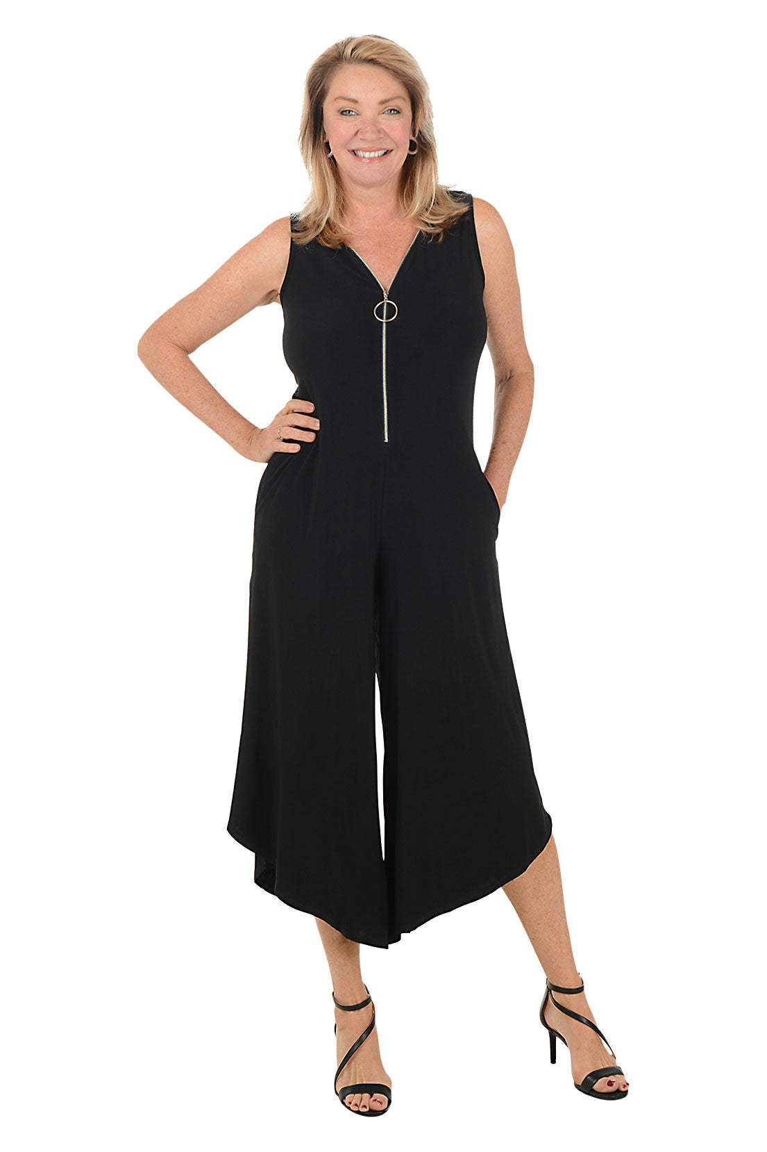 Woman wearing a black sleeveless jumpsuit with a zipper on a white background.