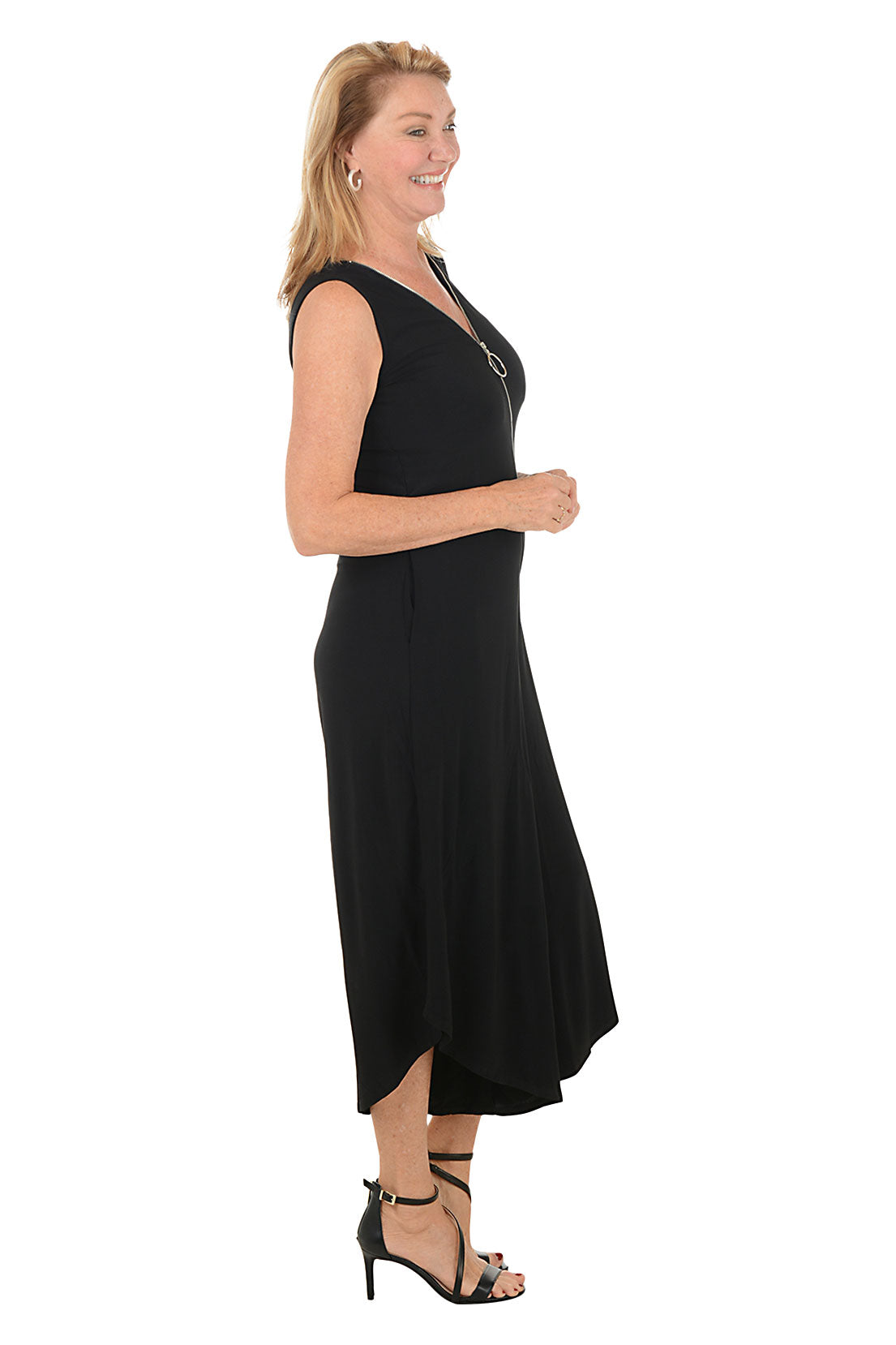 Woman wearing a black sleeveless jumpsuit with a zipper on a white background. Side shot.