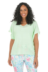 Woman wearing a light green top and colorful pants on a white background.
