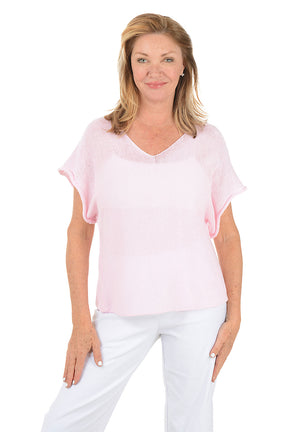 Woman wearing a light pink blouse and white pants on a white background.