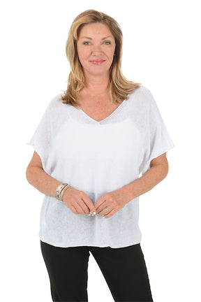 Woman wearing a white top and black pants on a white background.