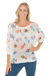 Woman wearing a white sweater with colorful fish patterns on a white background.