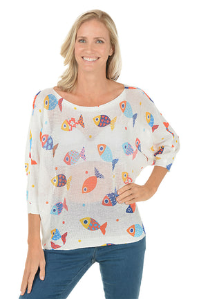 Woman wearing a white sweater with colorful fish patterns on a white background.