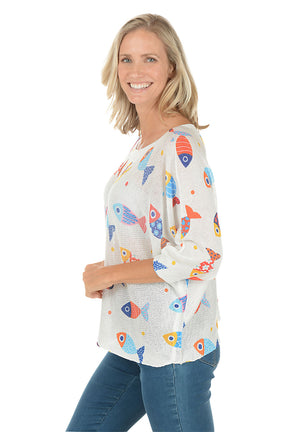 Woman wearing a white sweater with colorful fish patterns on a white background. Side shot.