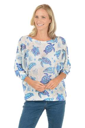 Woman wearing a blue turtle patterned shirt on a white background. Second front shot.