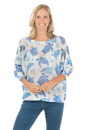 Woman wearing a blue turtle patterned shirt on a white background.