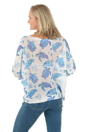 Woman wearing a blue turtle patterned shirt on a white background. Back shot.