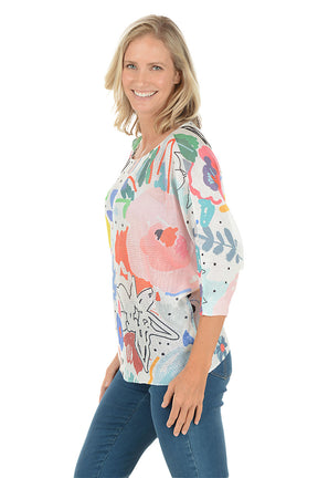 Woman wearing a colorful abstract patterned top on a white background. Side shot.