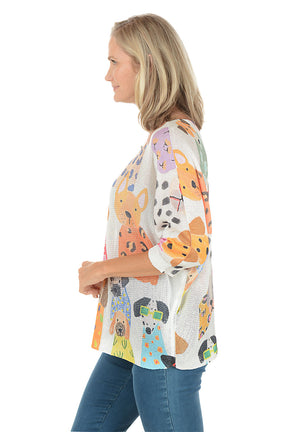 Woman wearing a colorful dog-patterned shirt on a white background. Side shot.