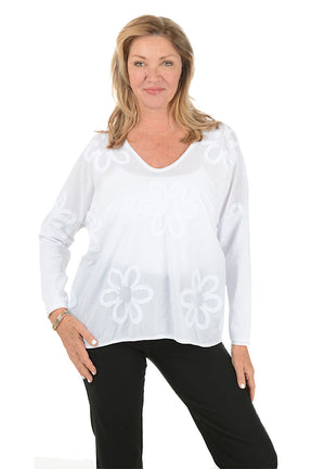 Woman wearing a white blouse with a floral pattern on a white background.
