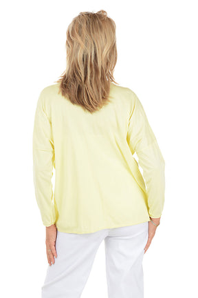 Woman wearing a light yellow floral blouse and white pants on a white background. Back shot.