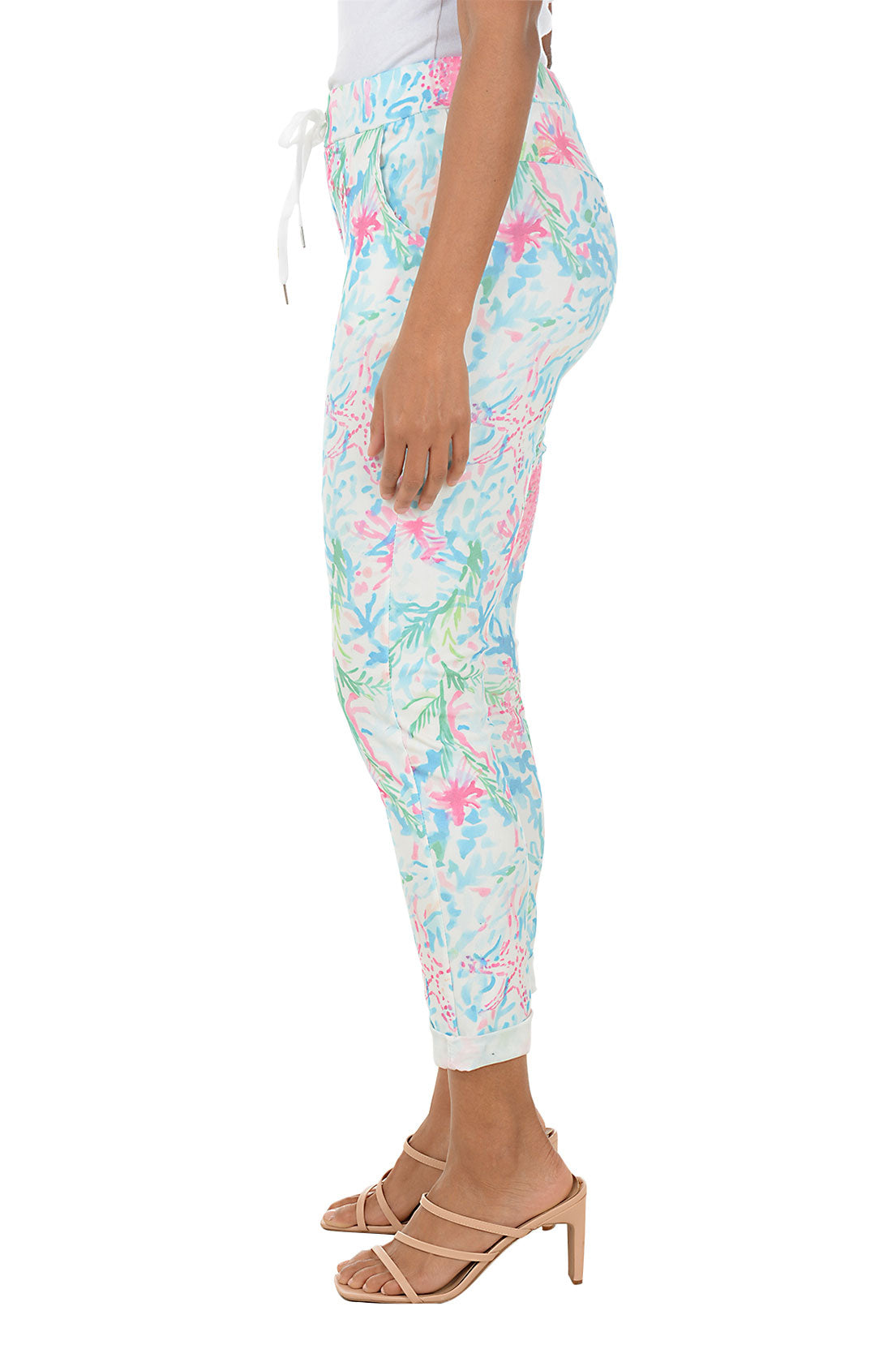 Person wearing colorful floral jogger pants on a white background. Side shot.