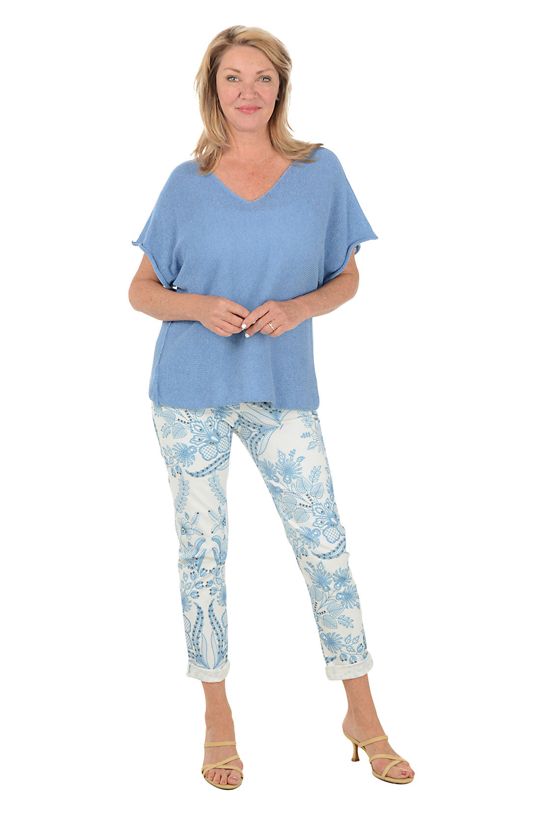 Woman wearing a blue top and light blue floral pants on a white background