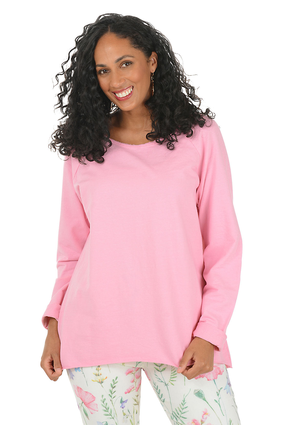 Woman wearing a pink long-sleeve top and floral pants on a white background.