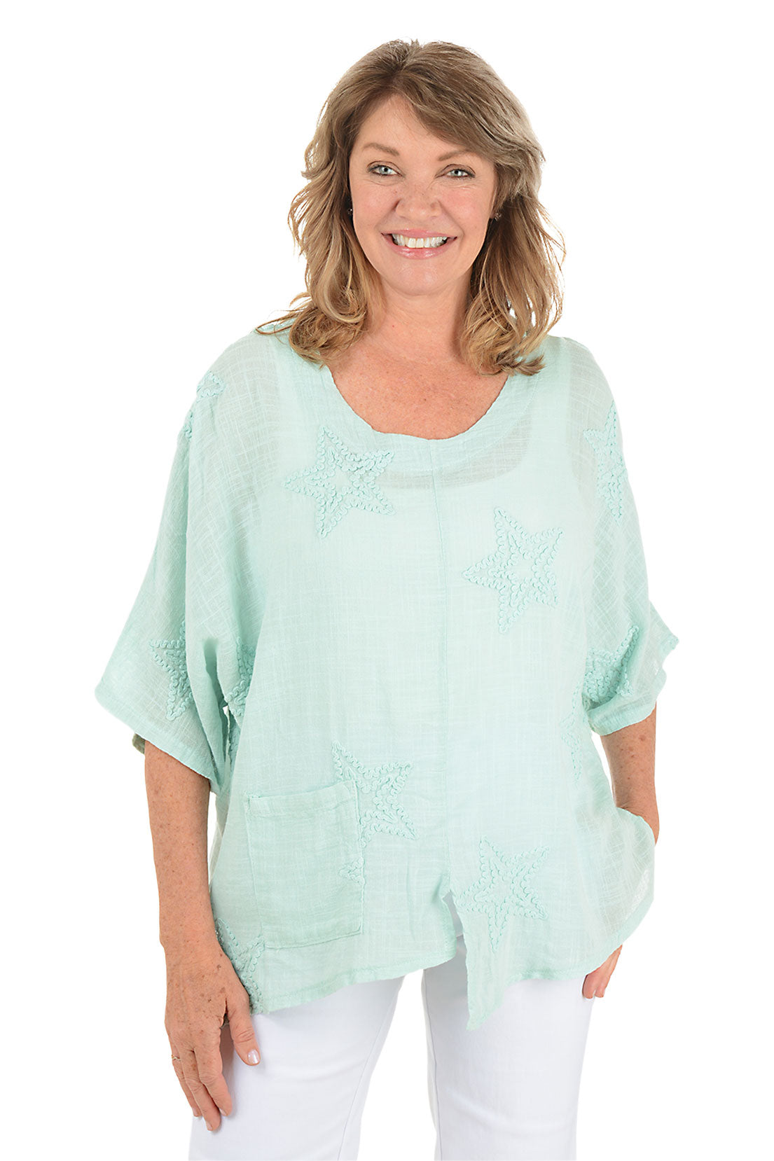 Woman wearing a green blouse with black pants on a white background.