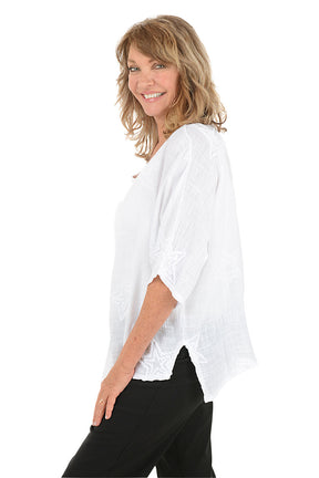 Woman wearing a white blouse with black pants on a white background. Side shot.