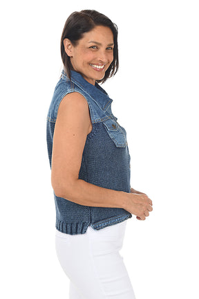 Woman wearing a blue denim vest over a white top on a white background. Side shot.