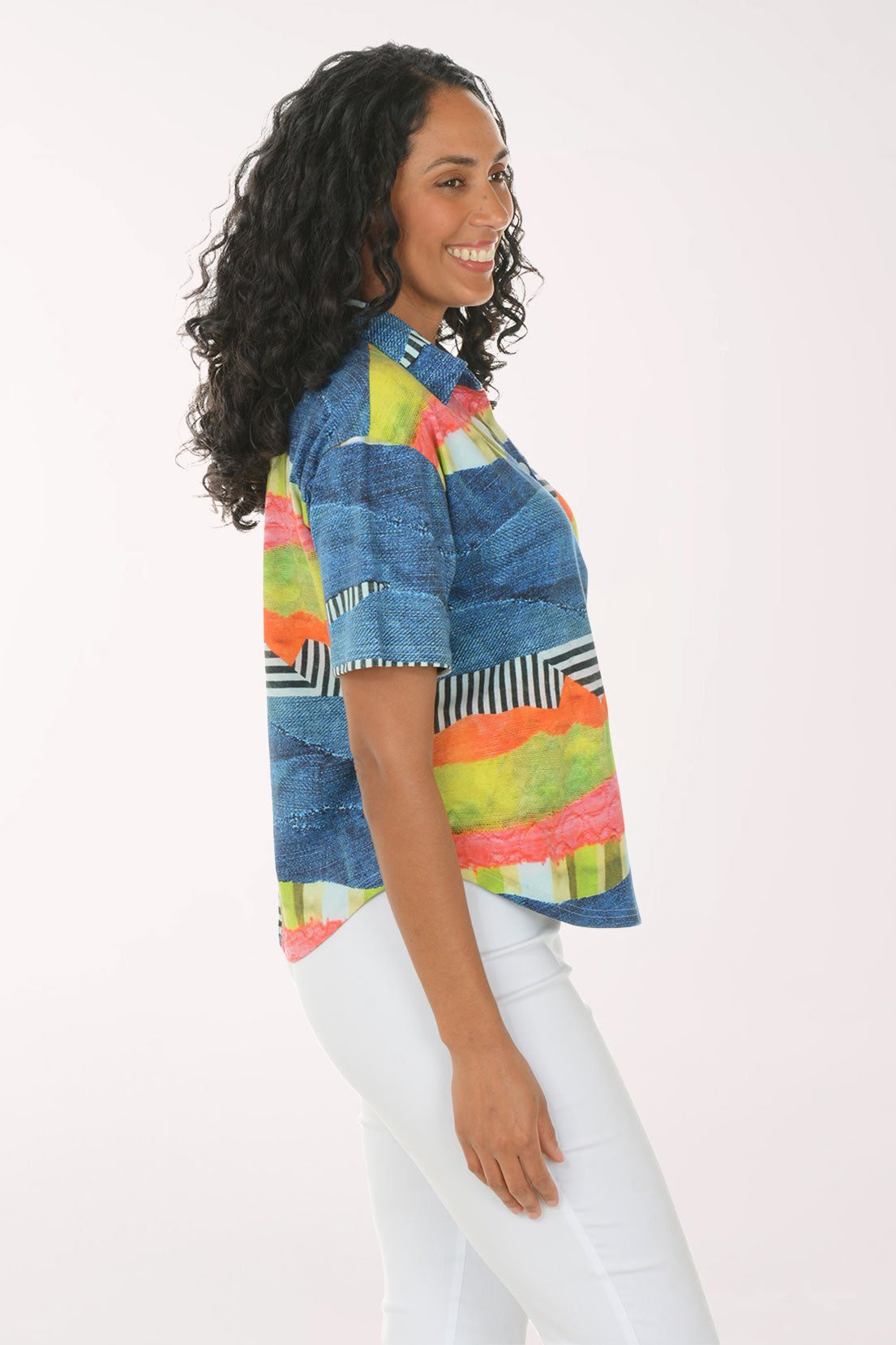 Woman wearing a colorful striped shirt and white pants on a white background