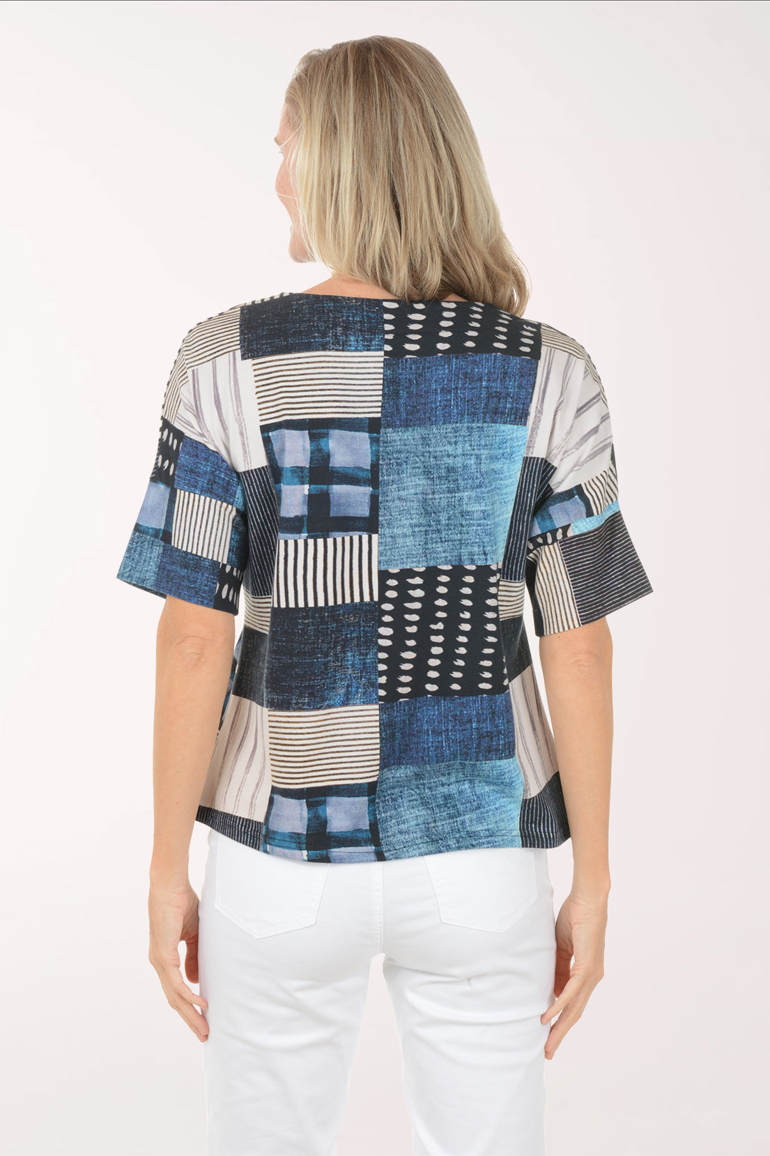 Woman wearing a patchwork top with blue, black, and white patterns on a white background