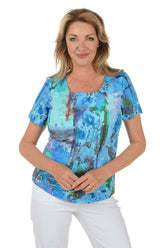 Woman wearing a colorful floral blouse against a white background.