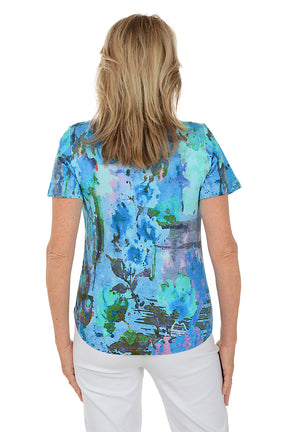 Woman wearing a colorful floral blouse against a white background. Back shot.