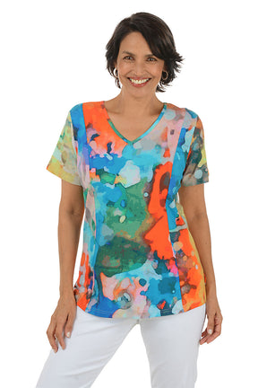 Woman wearing a colorful abstract patterned top on a white background.