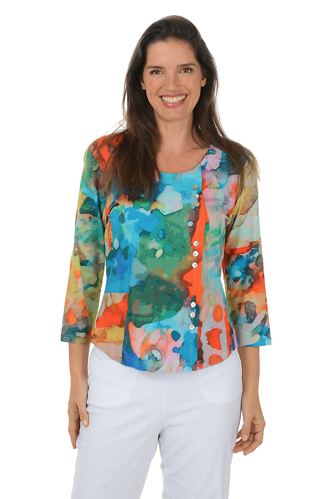 Woman wearing a colorful floral blouse with white pants on a white background.