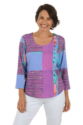 Woman wearing a colorful patterned top with white pants on a white background