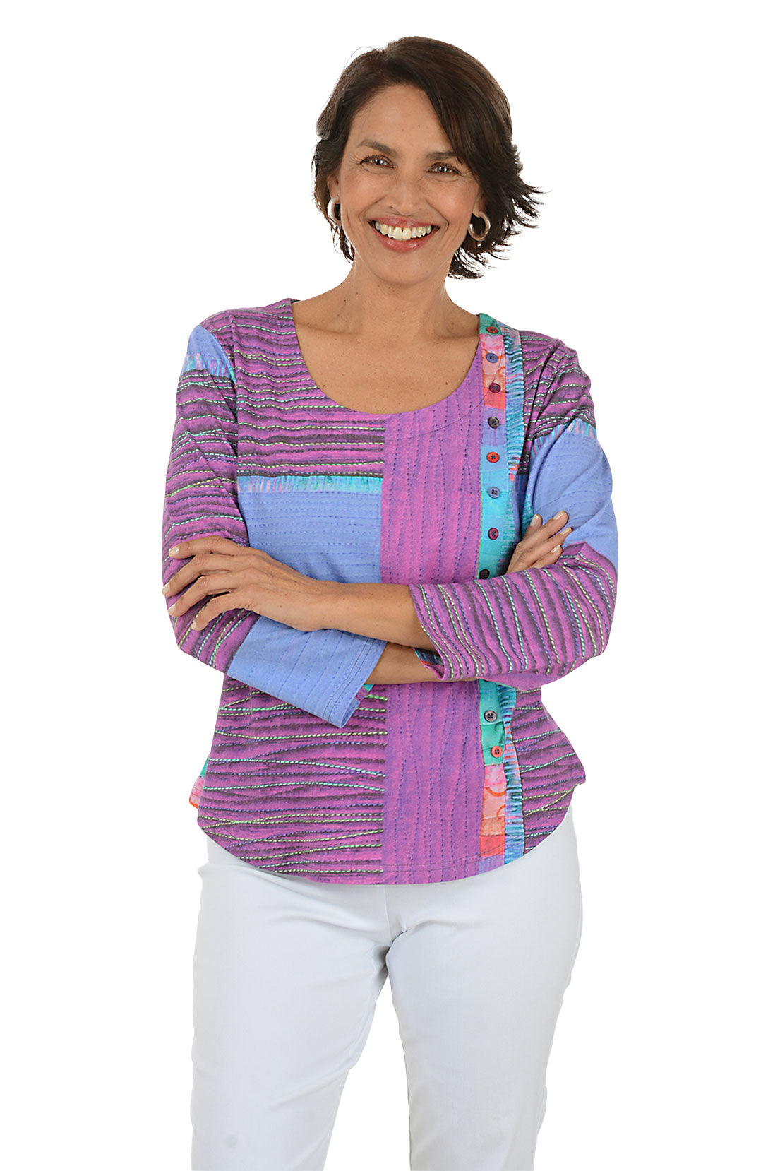 Woman wearing a colorful patterned top with white pants on a white background