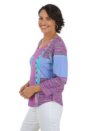Woman wearing a colorful patterned top with white pants on a white background
